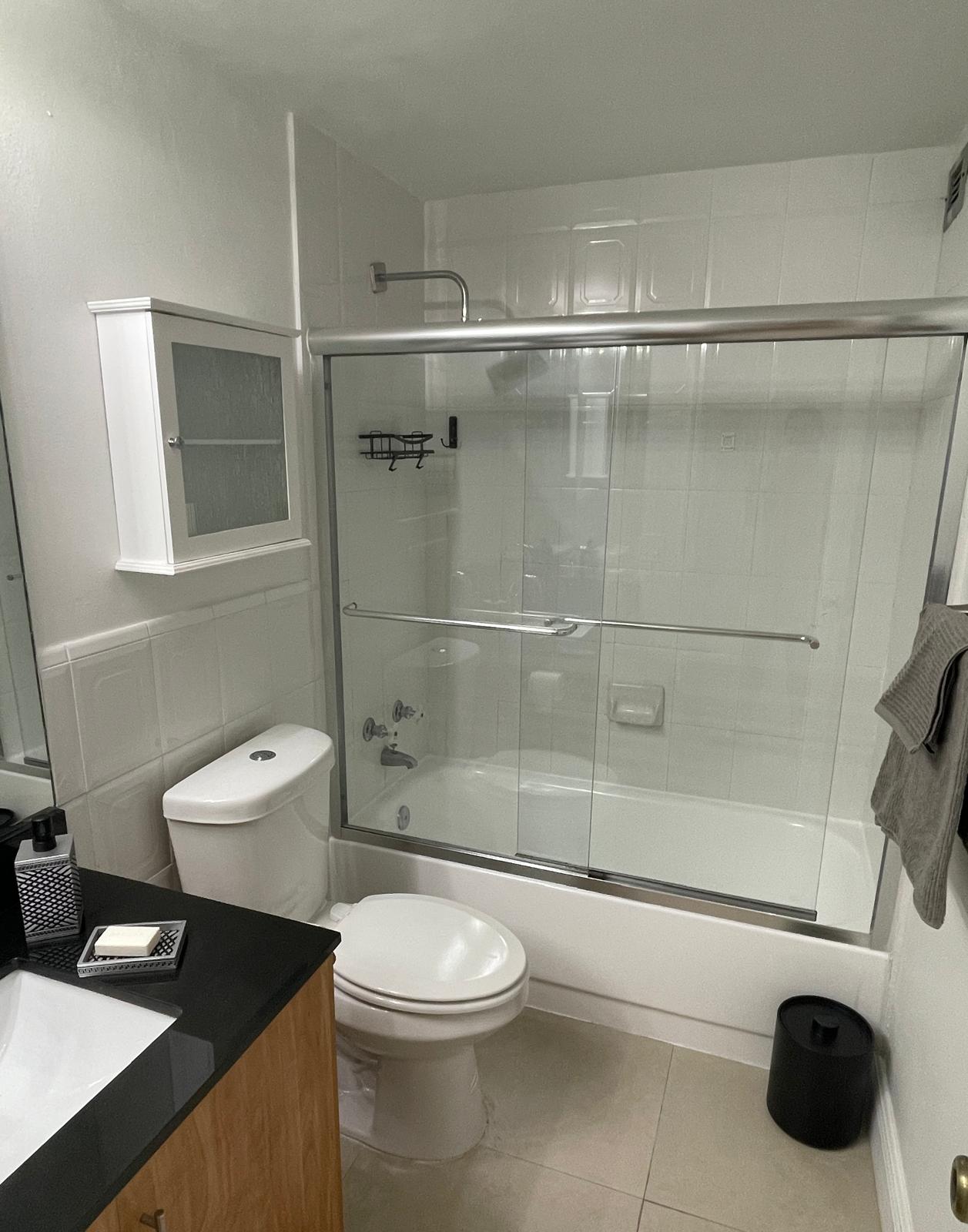 Bathroom with glass sliding shower doors over the tub and black granite vanity
