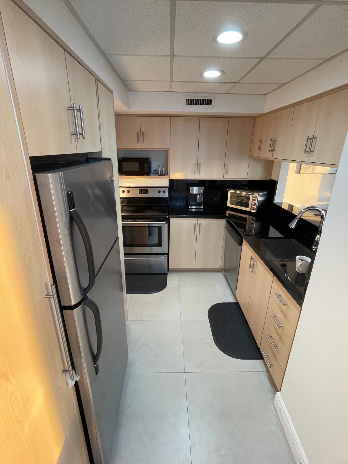 Fully equipped kitchen with stainless refrigerator, range and maple cabinetry