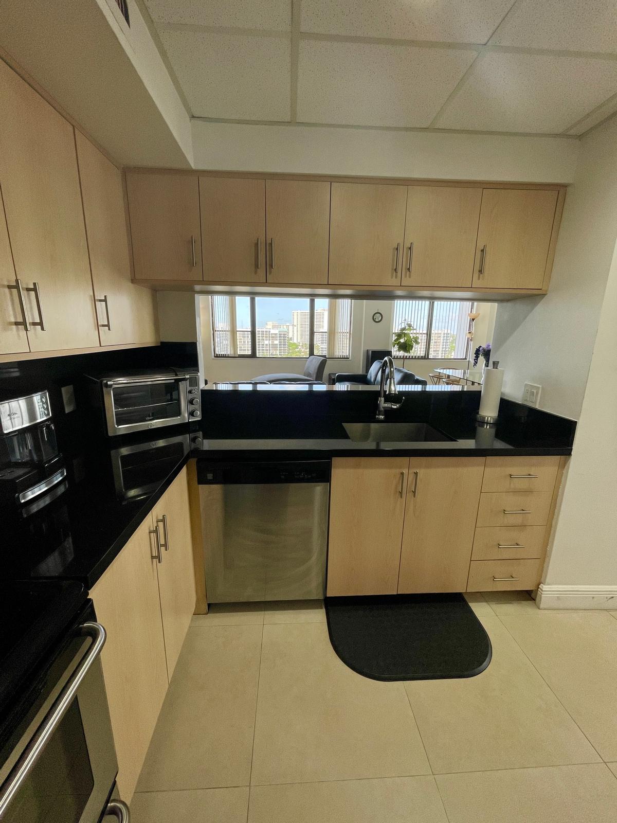 Kitchen with black granite counters, stainless appliances and a pass-through opening to the living room