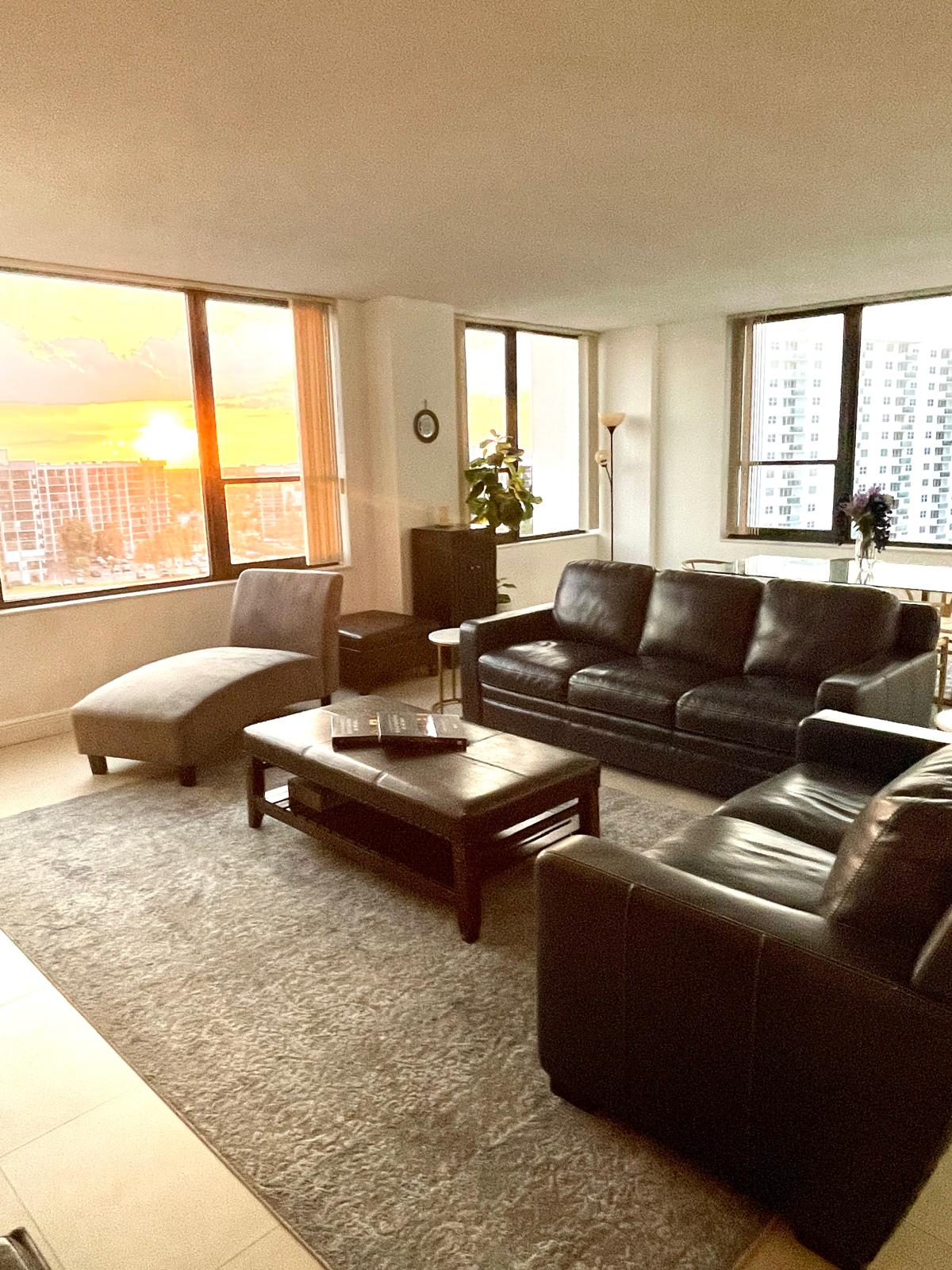 Leather sofas and chaise in the living room, warm sunset light pouring through corner windows